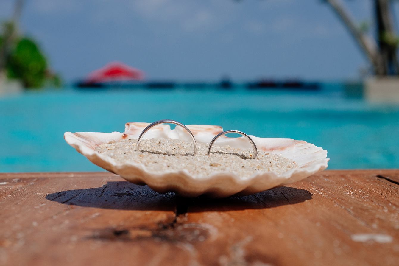 Strandhochzeit Koh Phangan. Die Hochzeitsringe liebevoll in einer mit Sand gefüllten Muschel dekoriert.