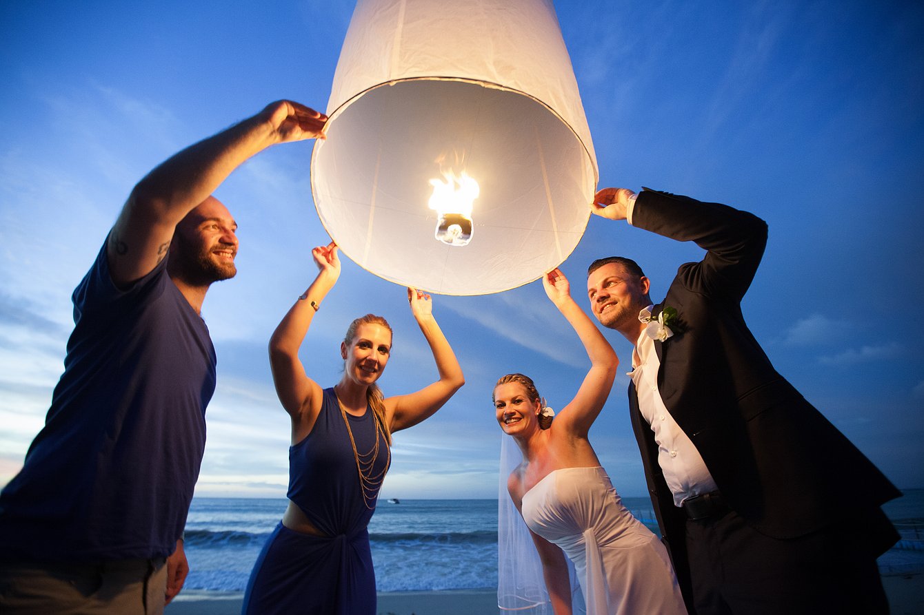 Wedding guests with a sky lantern on the beach in Thailand