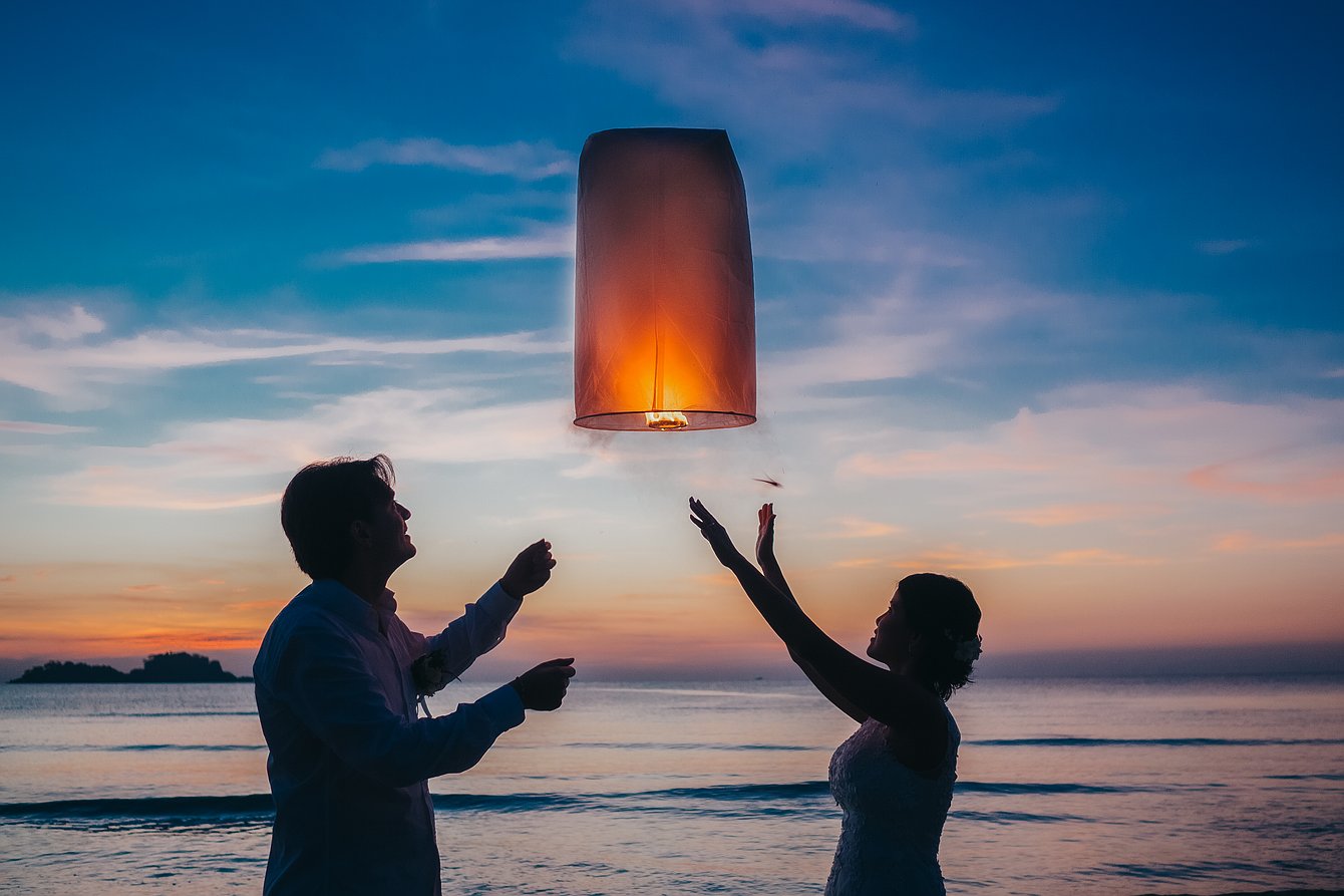 Bride and groom with flying lantern at sunset