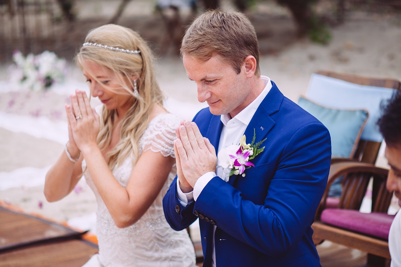 The Buddhist wedding ceremony in Thailand - the bride and groom kneel with folded hands before the monks