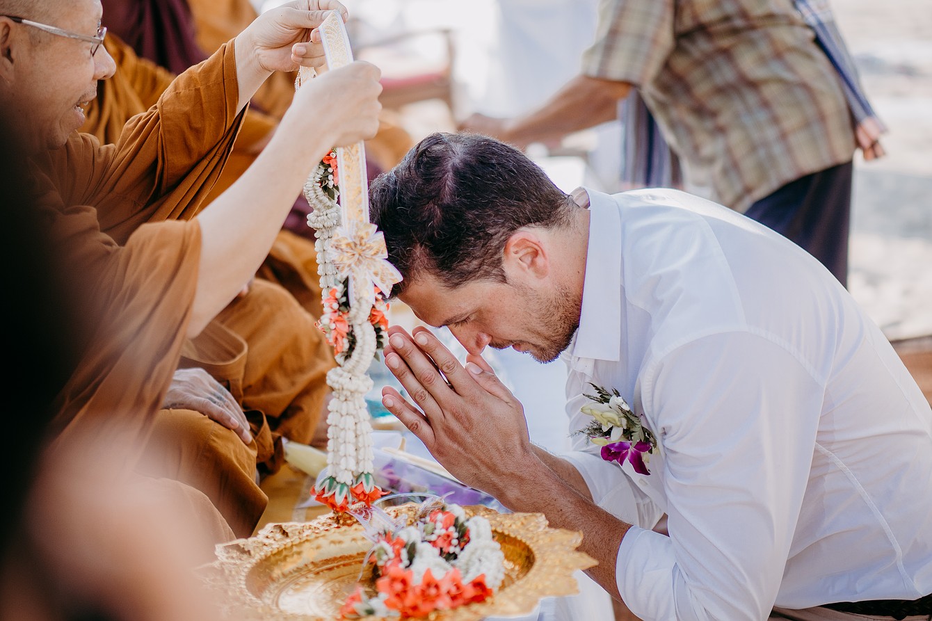 Buddha Wedding Thailand- Monk hangs flower garland around groom