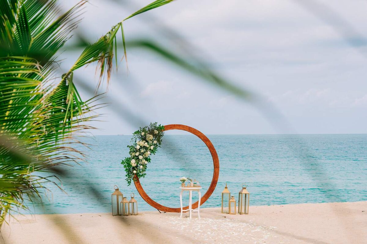Romantic beach wedding setup with a floral circle arch and lanterns on the sand at New Star Beach Resort, Koh Samui.